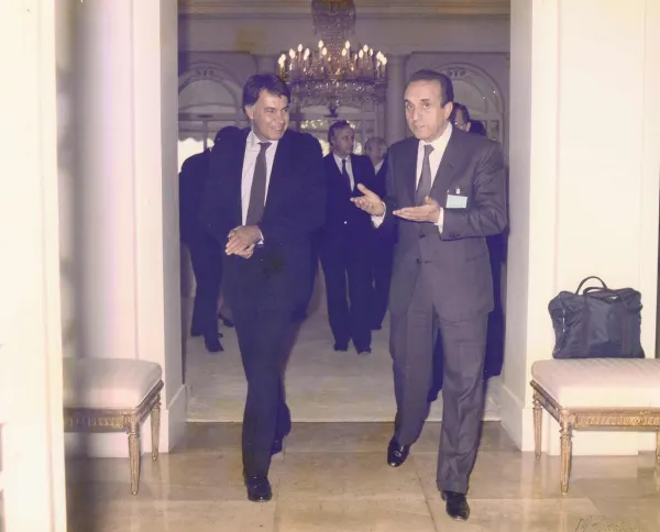 Gian Carlo Ruffino cammina con un collega in un corridoio di un palazzo istituzionale